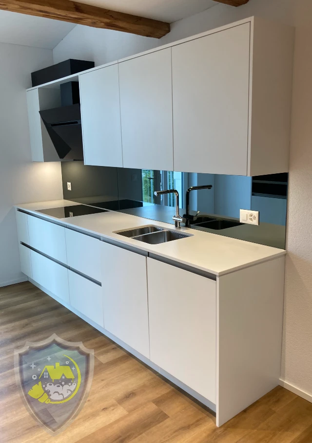 Saubere Küche mit gereinigten Schränken, glänzender Spüle und Kochfeld nach professioneller Reinigung.