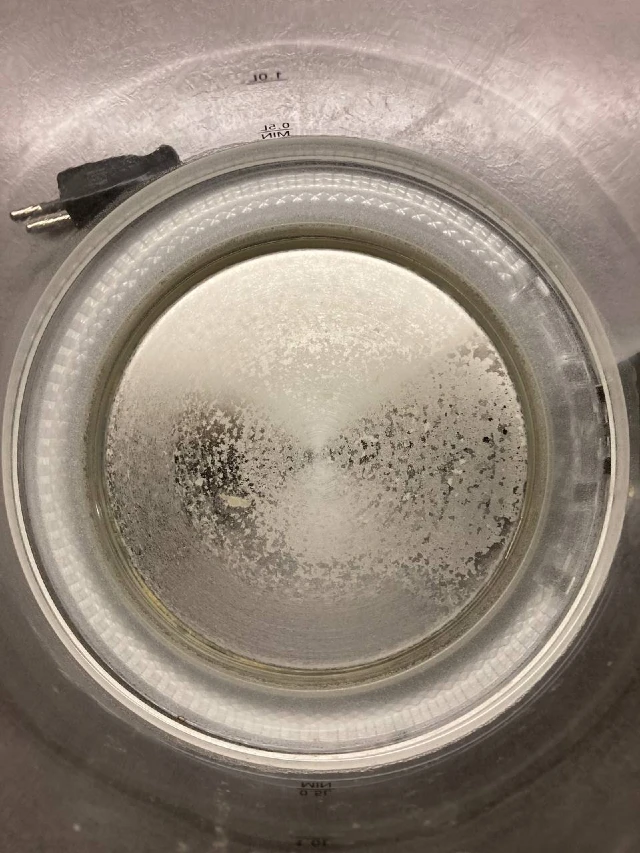 Innenraum eines Heißwasserkessels mit dicker Kalkschicht vor der Reinigung.